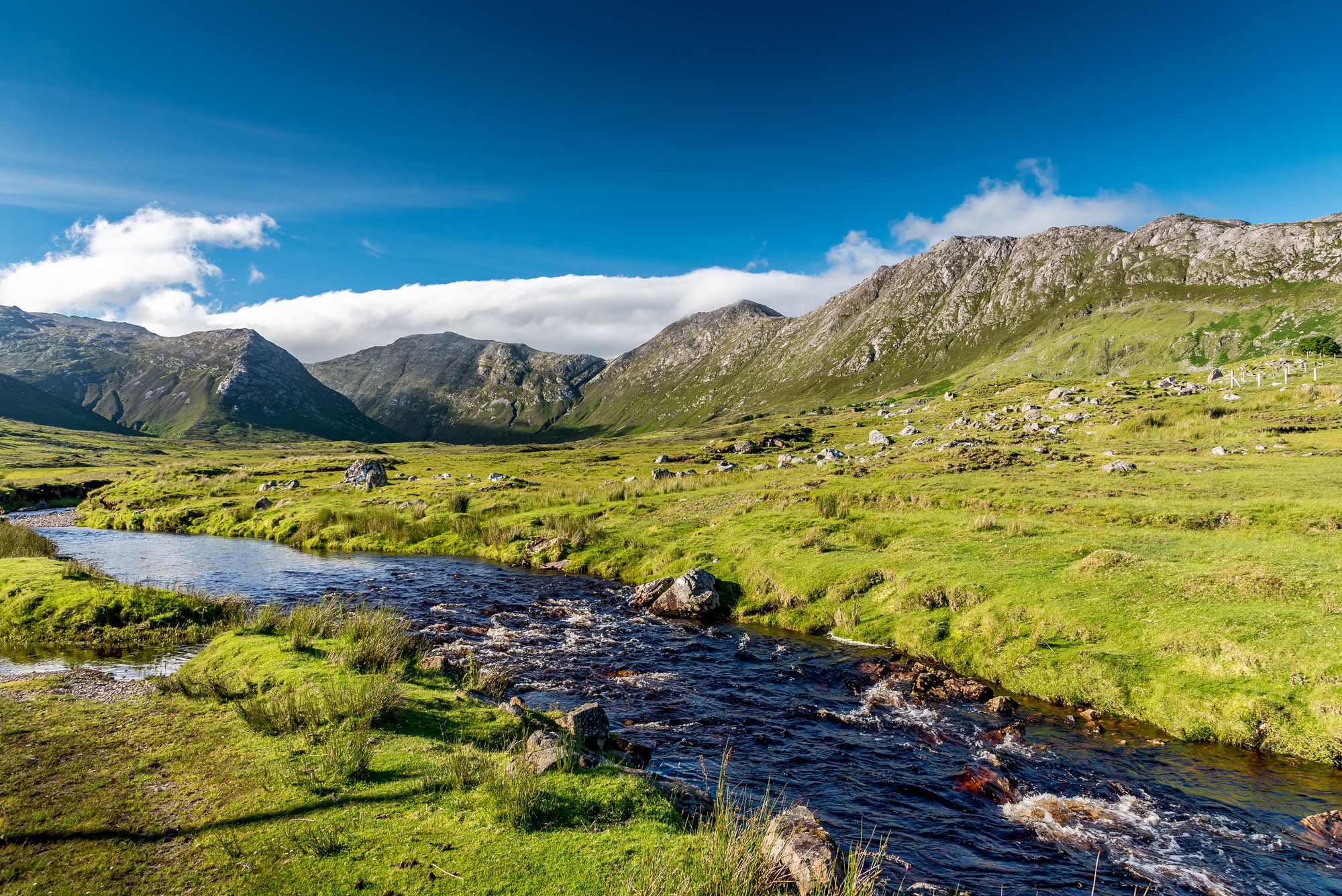 A river through the meadows in front of the Twelve Bens quartzite range in Connemara